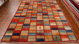This piece is made up of a grid of colours.  9 across the width and 14 the length, in total therefore 126 boxes.   Each row on the grid has a red border breaking up the boxes.   The colour palette used in this rug are a range of blues, greens, yellows, oranges and plum.  Each box has two of the colours blended.  In a couple of the boxes there are small depictions of fauna, animals or humans.  