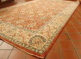 Soft terracotta ground with a cream and blue floral decorative pattern upon it.  There is a border in cream that has the same decorative pattern  but using the terracotta and blue.  Highlights in soft green. 