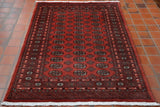 A rusty red ground with a green, peach and cream pattern design with the highlights for the pattern work being in black.  The design is a standard classic Bokhara design.  